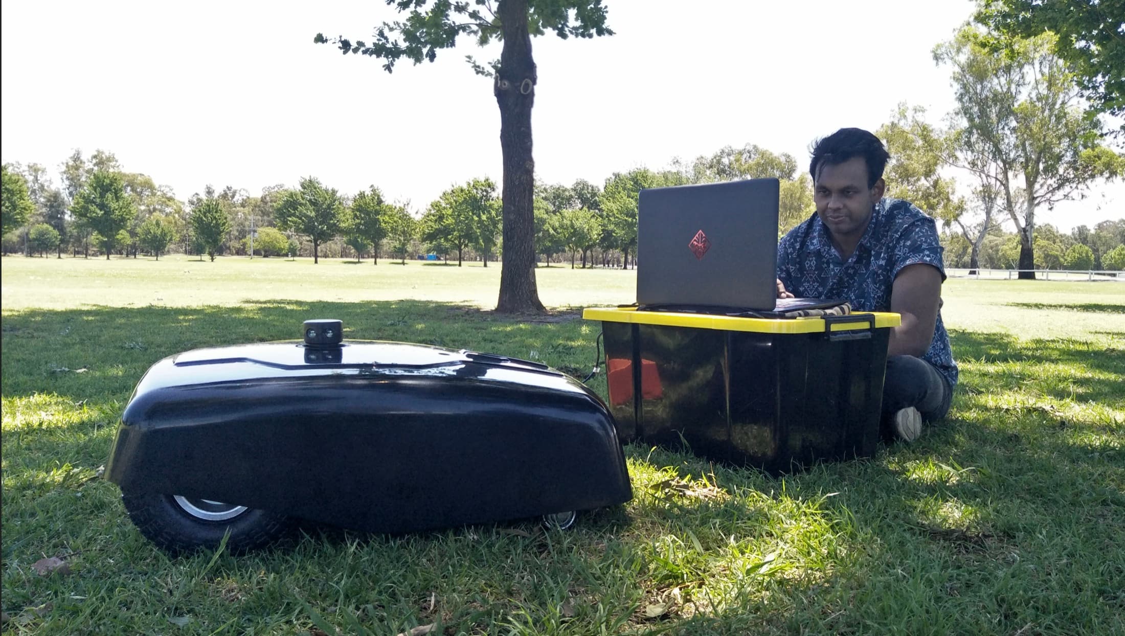 Sahil Harriram working beside the autonomous mower during a field test.